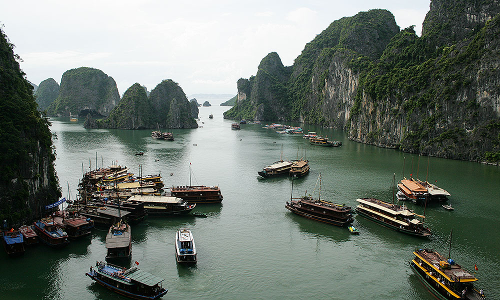 Viele Schiffe vor Felsen in der Halong-Bucht