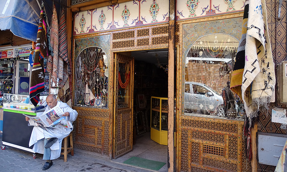 Mann mit Zeitung sitzt vor Geschäft in Taroudant