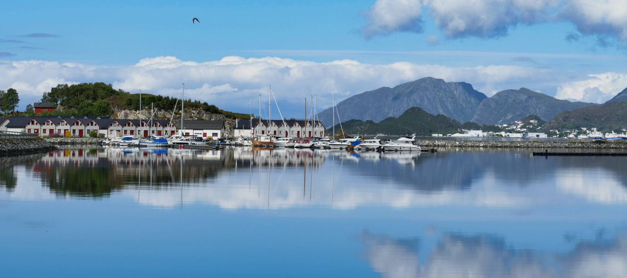 Kleiner Hafen mit Holzhäusern spiegelt sich im Wasser